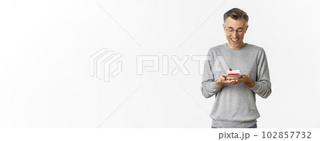 Portrait of handsome middle-aged man, looking happy at delicious cake, standing over white background Portrait of handsome middle-aged man, looking happy at delicious cake, standing over white background 102857732