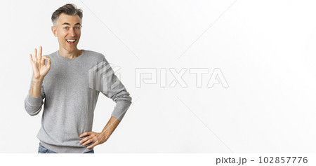 Image of handsome and cheerful middle-aged man showing support, make okay sign and smiling satisfied, approve and agree, saying yes, standing over white background 102857776