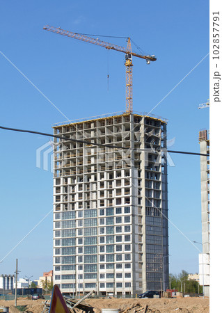 Construction site. Reinforced concrete frame of a multi-storey building and construction cranes. The final stage of construction. Against the background of the blue sky. 102857791
