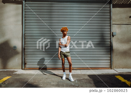 Stylish teenager with curly hair and makeup posing on the street 102860025