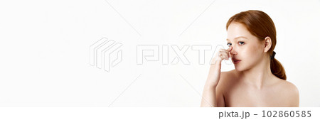 Portrait of tender, beautiful, young redhead girl touching nose against white studio background. Rhinoplasty. Banner Portrait of tender, beautiful, young redhead girl touching nose against white studio background. Rhinoplasty. Banner 102860585