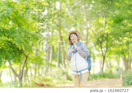 新緑の中でハイキングするシニア女性の写真 新緑の中でハイキングするシニア女性の写真 102860727