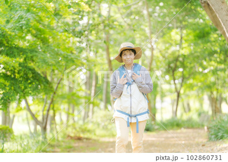 新緑の中でハイキングするシニア女性の写真 102860731