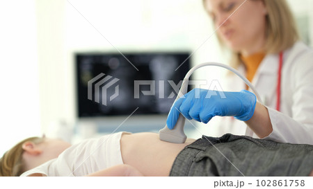 Doctor of ultrasound diagnostics making ultrasound of liver and bile ducts to child in clinic closeup Doctor of ultrasound diagnostics making ultrasound of liver and bile ducts to child in clinic closeup 102861758