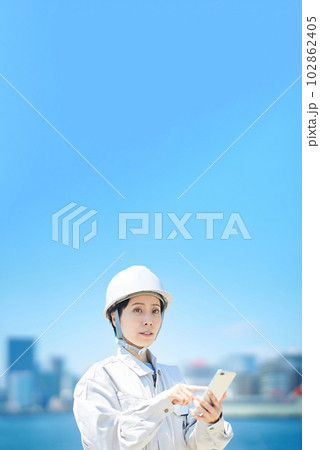 スマートフォンを手にする作業服姿の女性 スマートフォンを手にする作業服姿の女性 102862405