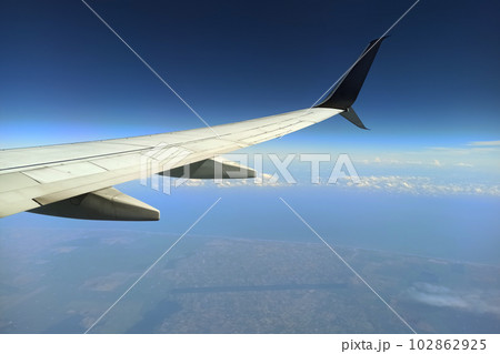 View through airplane window of commercial jet plane wing flying high in the sky. Air travelling concept View through airplane window of commercial jet plane wing flying high in the sky. Air travelling concept 102862925