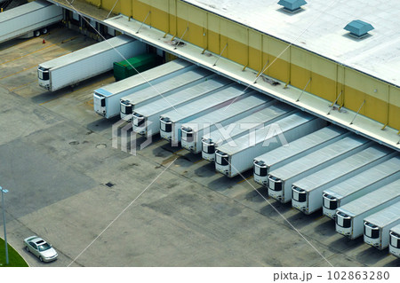 Top view of giant logistics center with many commercial trailer trucks unloading and uploading retail products for further shipment. Global economy concept 102863280
