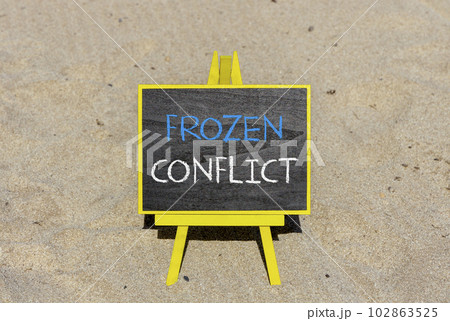 Frozen conflict symbol. Concept words Frozen conflict on beautiful black chalk blackboard on a beautiful sand beach background. Business and Frozen conflict concept. Copy space. 102863525
