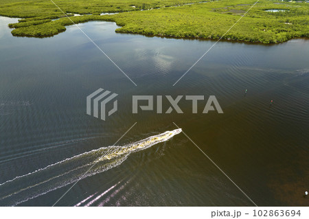 Overhead view of small boat on Everglades swamps with green vegetation between water inlets. Natural habitat of many tropical species in Florida wetlands 102863694