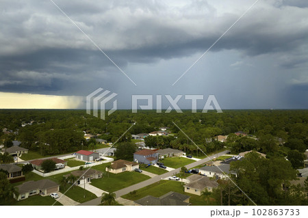 Landscape of dark ominous clouds forming on stormy sky during heavy thunderstorm over rural town area 102863733