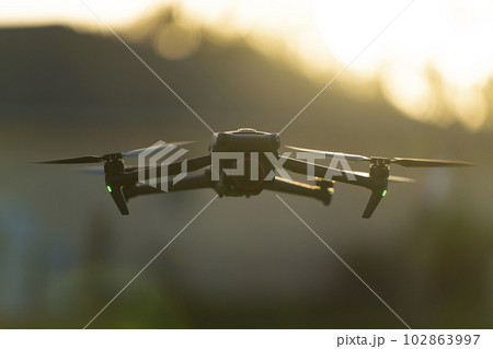 Drone with digital camera and fast rotating propellers flying taking video and pictures. Drone with digital camera and fast rotating propellers flying taking video and pictures. 102863997