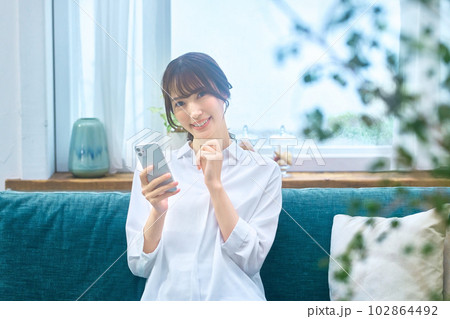 リビングでスマホを操作する若い主婦 リビングでスマホを操作する若い主婦 102864492
