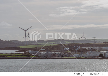 View of industrial buildings and wind farms from the waterfront of Cobh, Ireland. 102864826