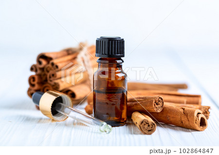 Dark glass bottle with cinnamon oil. Dark glass bottle with cinnamon oil. 102864847