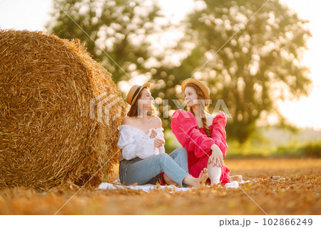 Two young women having fun near haystack. Fashion concept. Summer concept. 102866249
