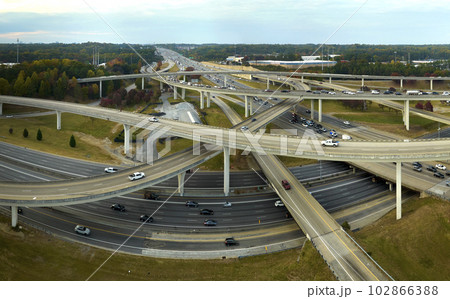 American freeway intersection with fast driving cars and trucks. View from above of USA transportation infrastructure American freeway intersection with fast driving cars and trucks. View from above of USA transportation infrastructure 102866388