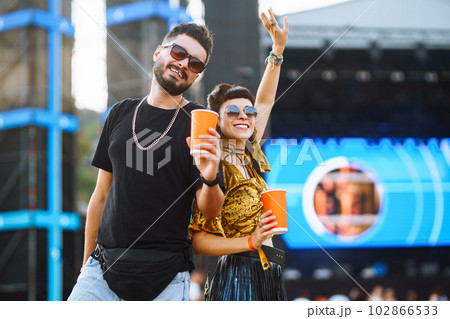 Lovely couple having fun at festival. Young friends with beer at beach party. Summer holiday, vacation. Lovely couple having fun at festival. Young friends with beer at beach party. Summer holiday, vacation. 102866533