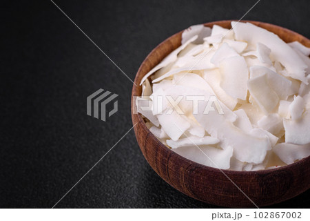 White dry coconut flakes in a wooden bowl prepared for making desserts 102867002