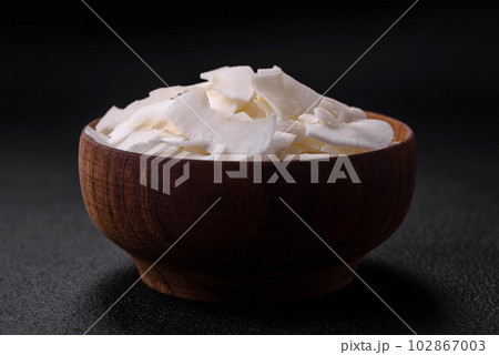White dry coconut flakes in a wooden bowl prepared for making desserts 102867003