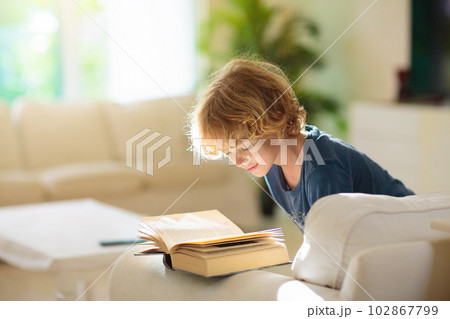 Child reading a book. Boy doing homework. 102867799