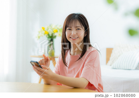 リビングでスマホを見る女性 102868080