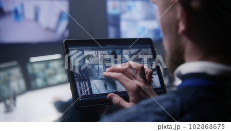 Security officer zoom CCTV cameras uses tablet Security officer zoom CCTV cameras uses tablet 102868675