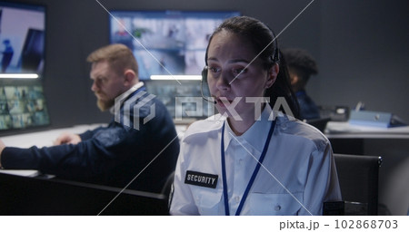 Female security operator in headset looks at screen Female security operator in headset looks at screen 102868703