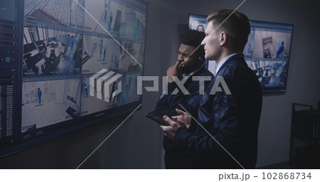Officer monitors cameras and talks with colleague 102868734