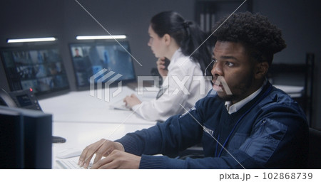 Security operator types keyboard and looks at monitor 102868739