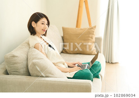 パソコンを使用する私服の若い女性　リビング　 102869034