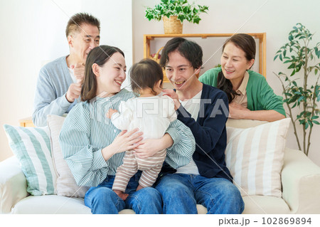 リビングでリラックスする三世代家族 102869894