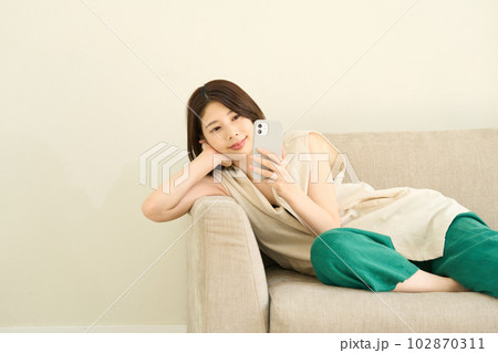 スマホを使用する私服の若い女性 リビング スマホを使用する私服の若い女性 リビング 102870311