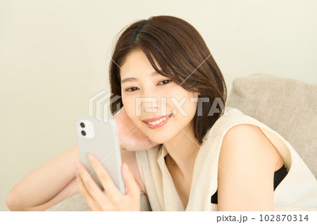 スマホを使用する私服の若い女性 リビング スマホを使用する私服の若い女性 リビング 102870314