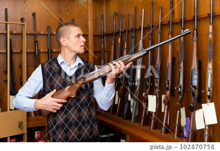 Buyer selects combat rifle at a gun store 102870758