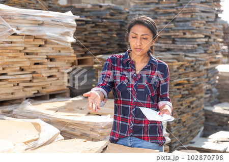 Female worker checking quantity of natural stone tiles 102870798