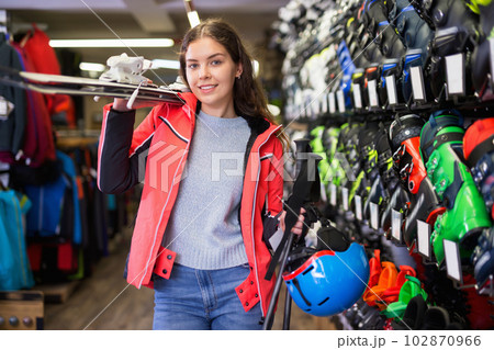 Smiling young girl chose skis, shelm and boots Smiling young girl chose skis, shelm and boots 102870966