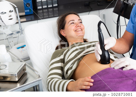 Woman getting ultrasound procedure for body contouring Woman getting ultrasound procedure for body contouring 102871001