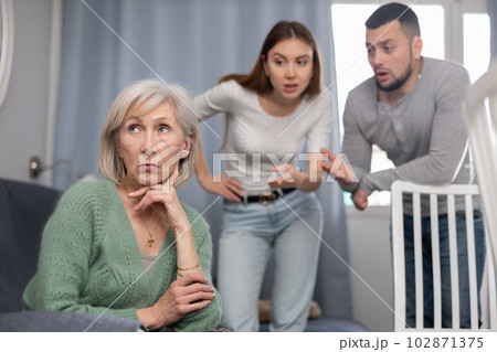Senior woman ignoring adult couple scolding her 102871375