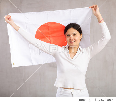 Reliant positive young woman holds big national flag of Japan with confident smile showing teeth 102871667