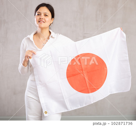 Reliant positive young woman holds big national flag of Japan with confident smile showing teeth 102871736