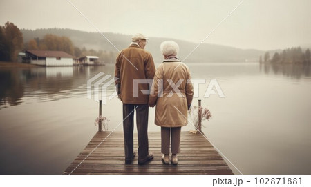 elderly gray-haired couple man and woman walking on the shore of the lake.  102871881