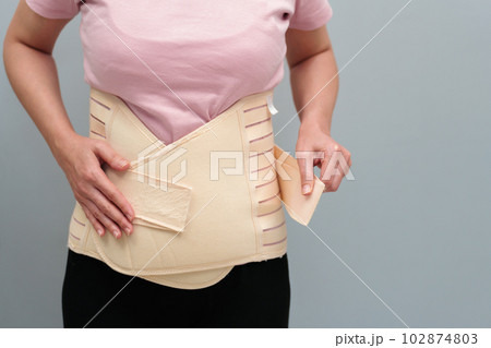 woman wearing lumbar support belts. pregnant and postnatal lumbar brace woman wearing lumbar support belts. pregnant and postnatal lumbar brace 102874803