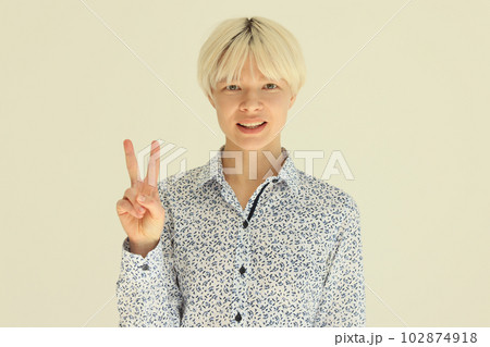 Smiling blonde woman showing victory V sign with fingers Smiling blonde woman showing victory V sign with fingers 102874918