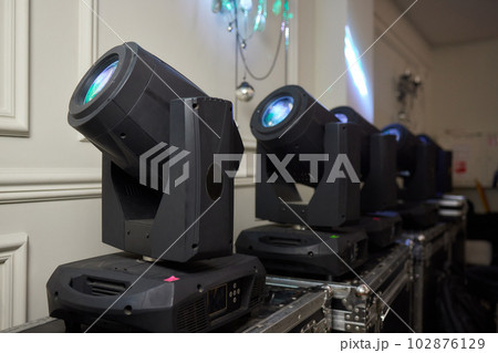 Installation of professional sound, light, video and stage equipment for a concert. Stage lighting equipment is clamped on a truss for lifting. Flight cases with cables. 102876129