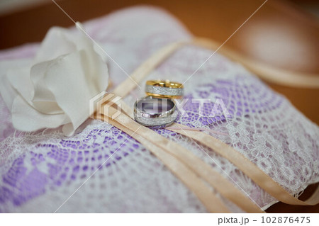 golden wedding rings on small blue and Turquoise cushion. 102876475