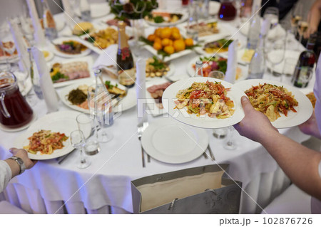 The waiter carries dishes at the festival. The girl brought a cheese plate. 102876726
