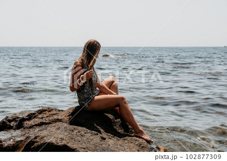 Woman summer travel sea. Happy tourist enjoy taking picture outdoors for memories. Woman traveler posing on the beach at sea surrounded by volcanic mountains, sharing travel adventure journey Woman summer travel sea. Happy tourist enjoy taking picture outdoors for memories. Woman traveler posing on the beach at sea surrounded by volcanic mountains, sharing travel adventure journey 102877309