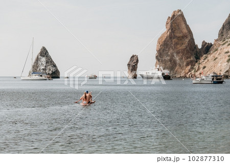 Family sea sup. Young happy father with his son and daughter Floating on a SUP board, paddling in blue sea water. summer vacation and Dad and Son Daughter concept. 102877310