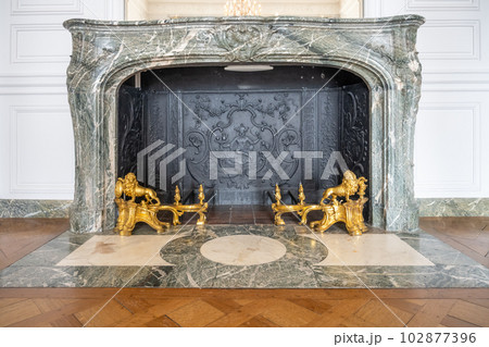 Old marble fireplace with golden forging. Chateau Versailles near Paris, France 102877396