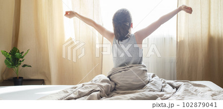 little boy sitting and stretching in bed at home in the morning on a window background 102879041